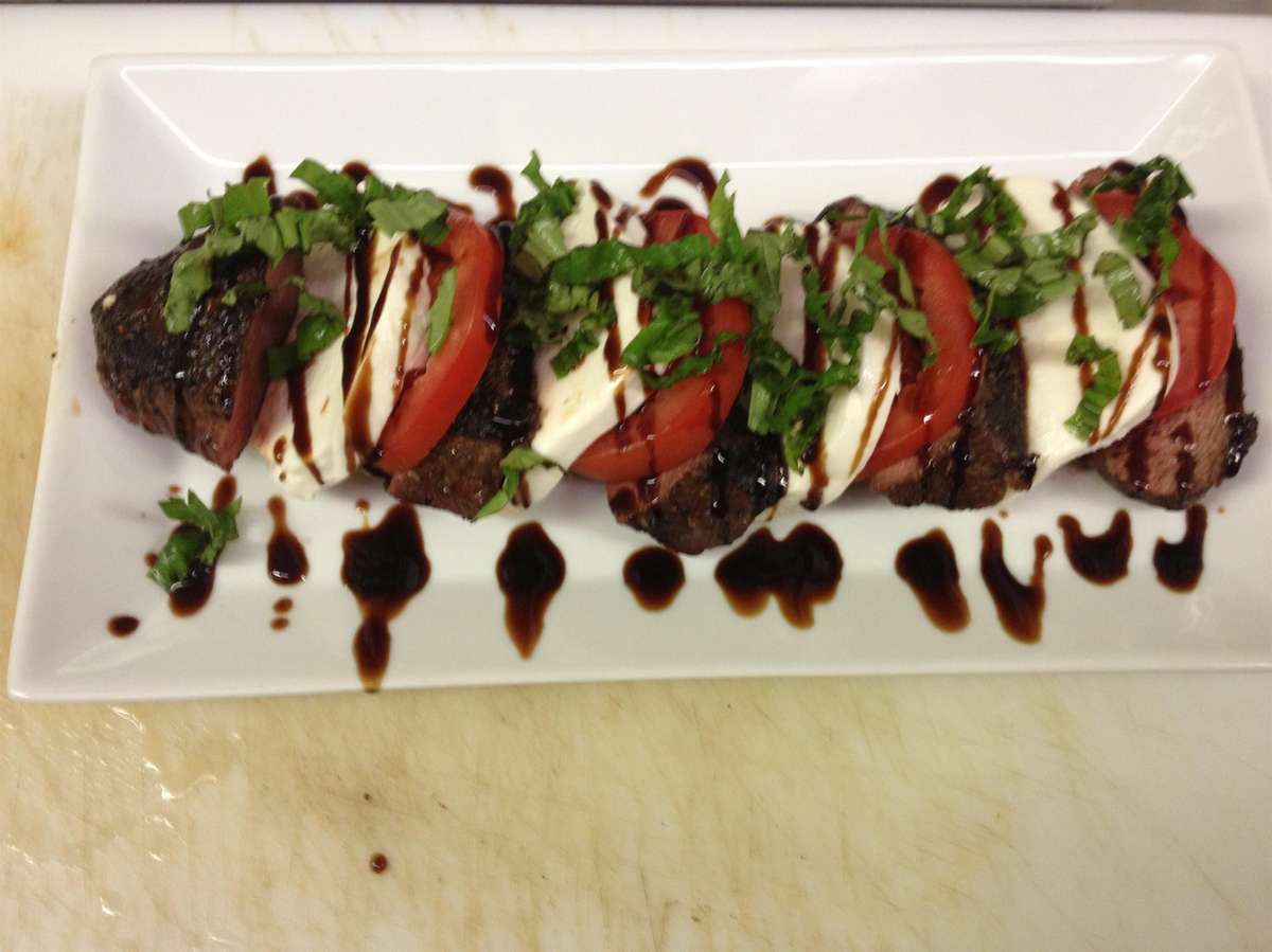 caprese salad with steal, mozzarella, tomatoes, herbs and a vinaigrette sauce