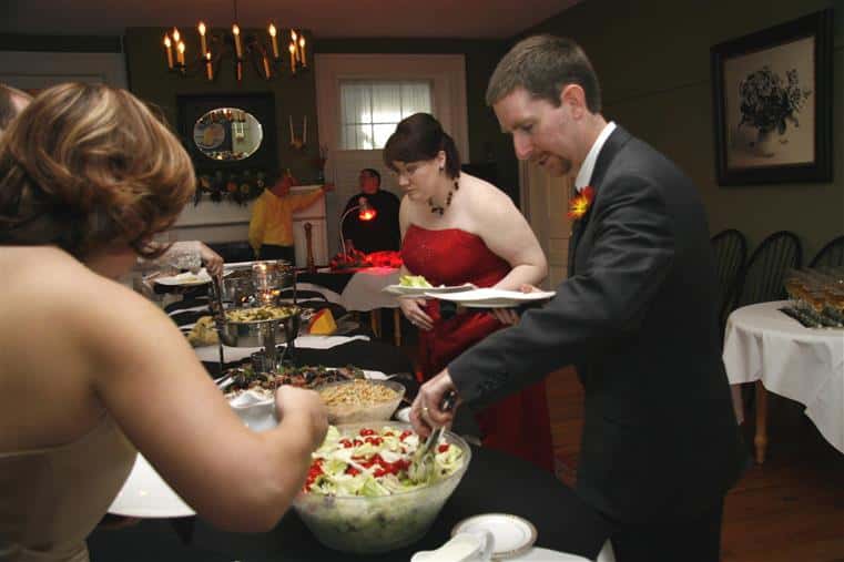 wedding guests together at a catering buffet station placing food onto their plates