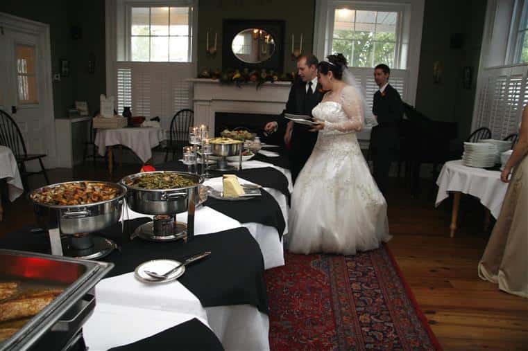 bride and groom at a catering buffet station placing food onto their plates