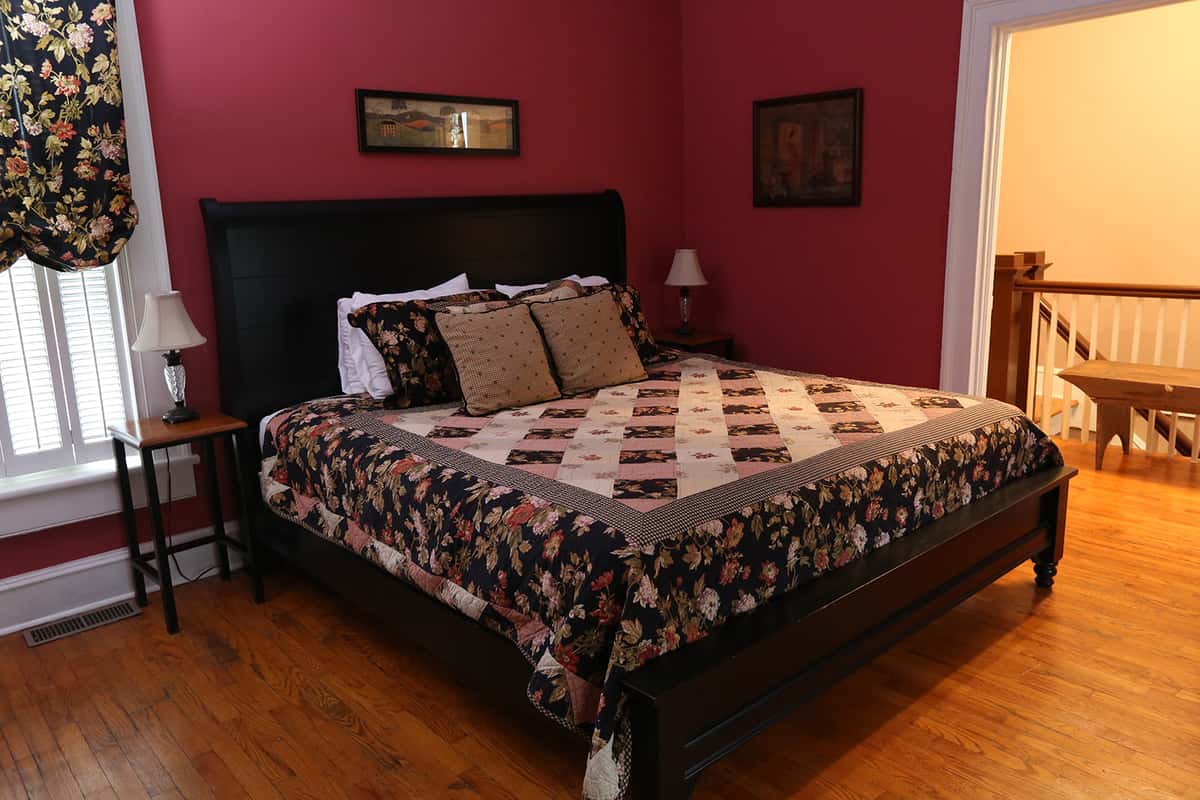 Red walls with queen size bed and black, red, and white quilt bedding with black head board