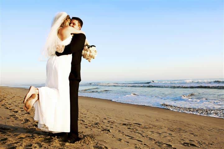 bride and groom embracing on the beach