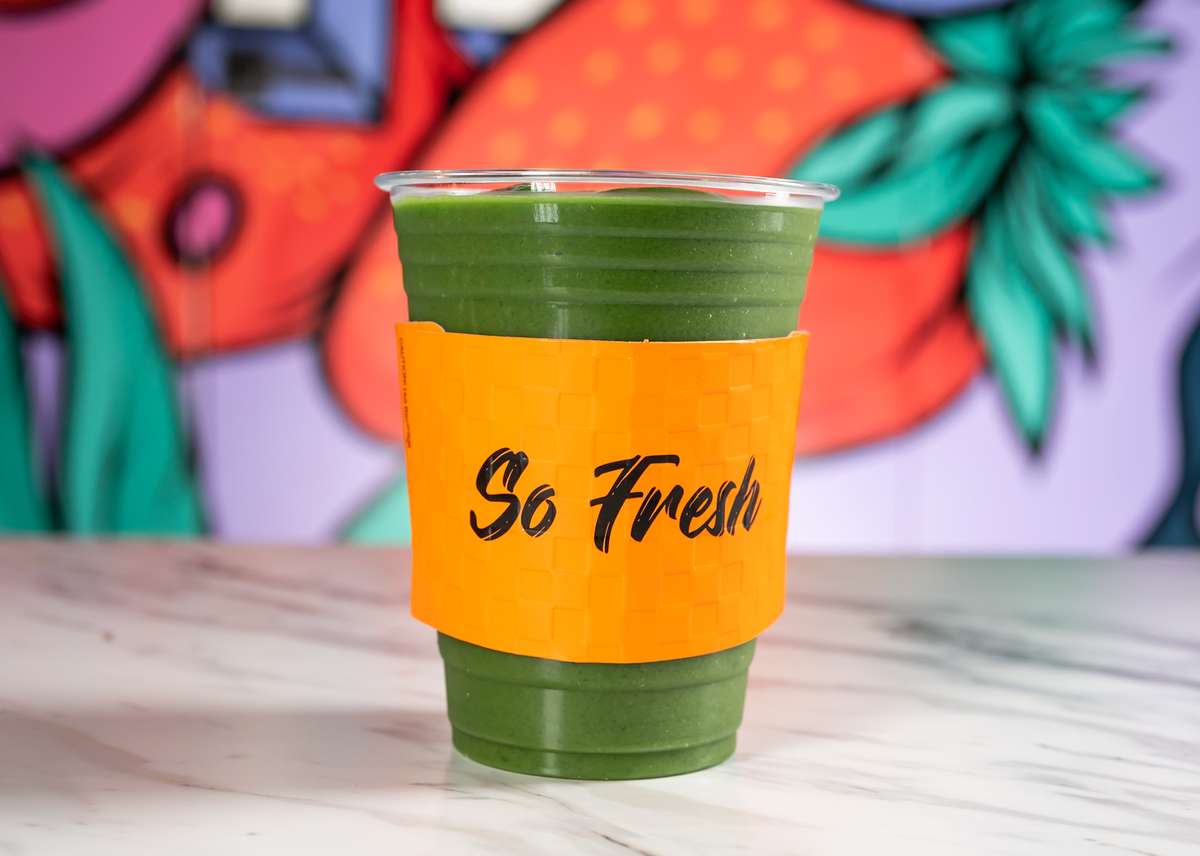 green juice with orange cup holder that reads so fresh