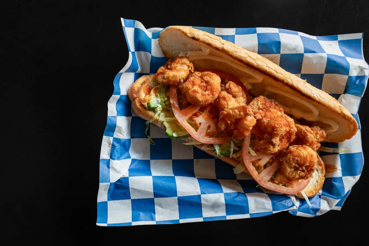 Crispy fried shrimp po' boy sandwich with lettuce, tomato, and remoulade sauce served on toasted French bread
