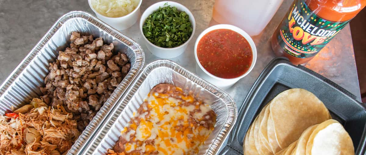 Taco catering pack with trays of meat, rice, beans tortillas and salsa