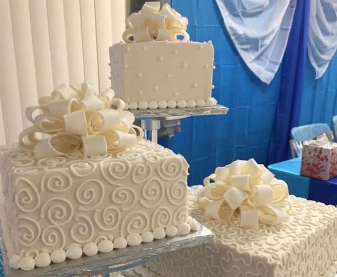 Image of white wedding cakes with piped decorations on cake stands