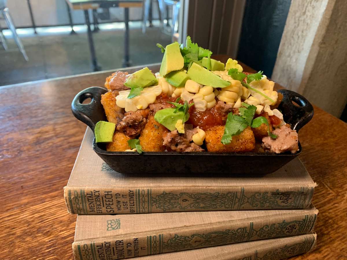 Loaded breakfast skillet with seasoned potatoes, avocado, and fresh herbs.