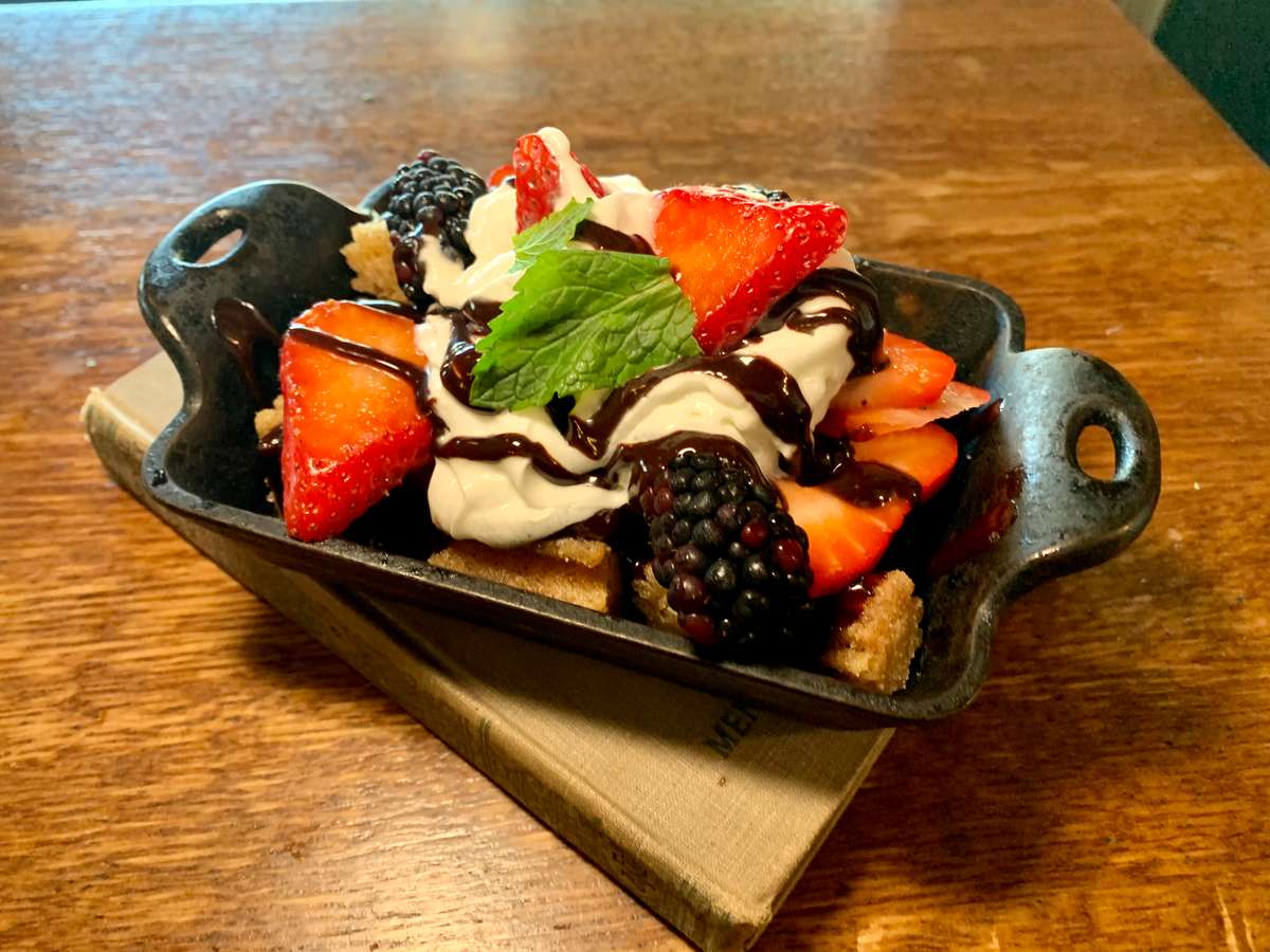 Fresh mixed berries topped with whipped cream and chocolate drizzle.