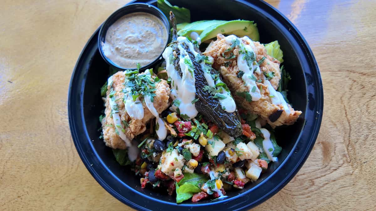 Mexican inspired bowl with grilled chicken, fresh vegetables, and creamy dressing.
