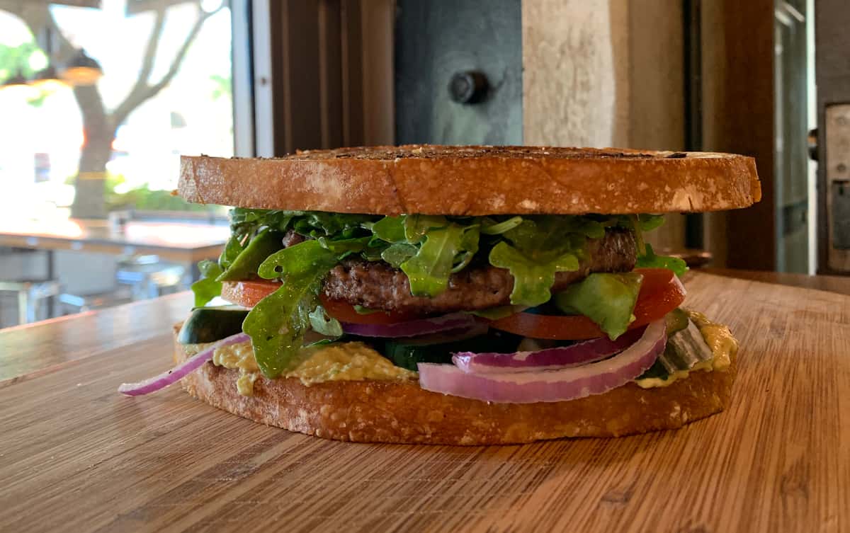 Gourmet burger stacked with fresh vegetables and savory toppings.