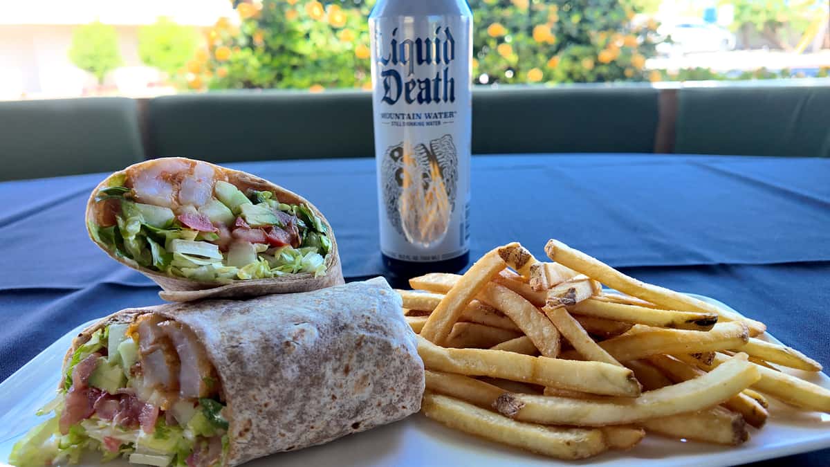 Tempura shrimp wrap served with golden fries and a canned beverage.