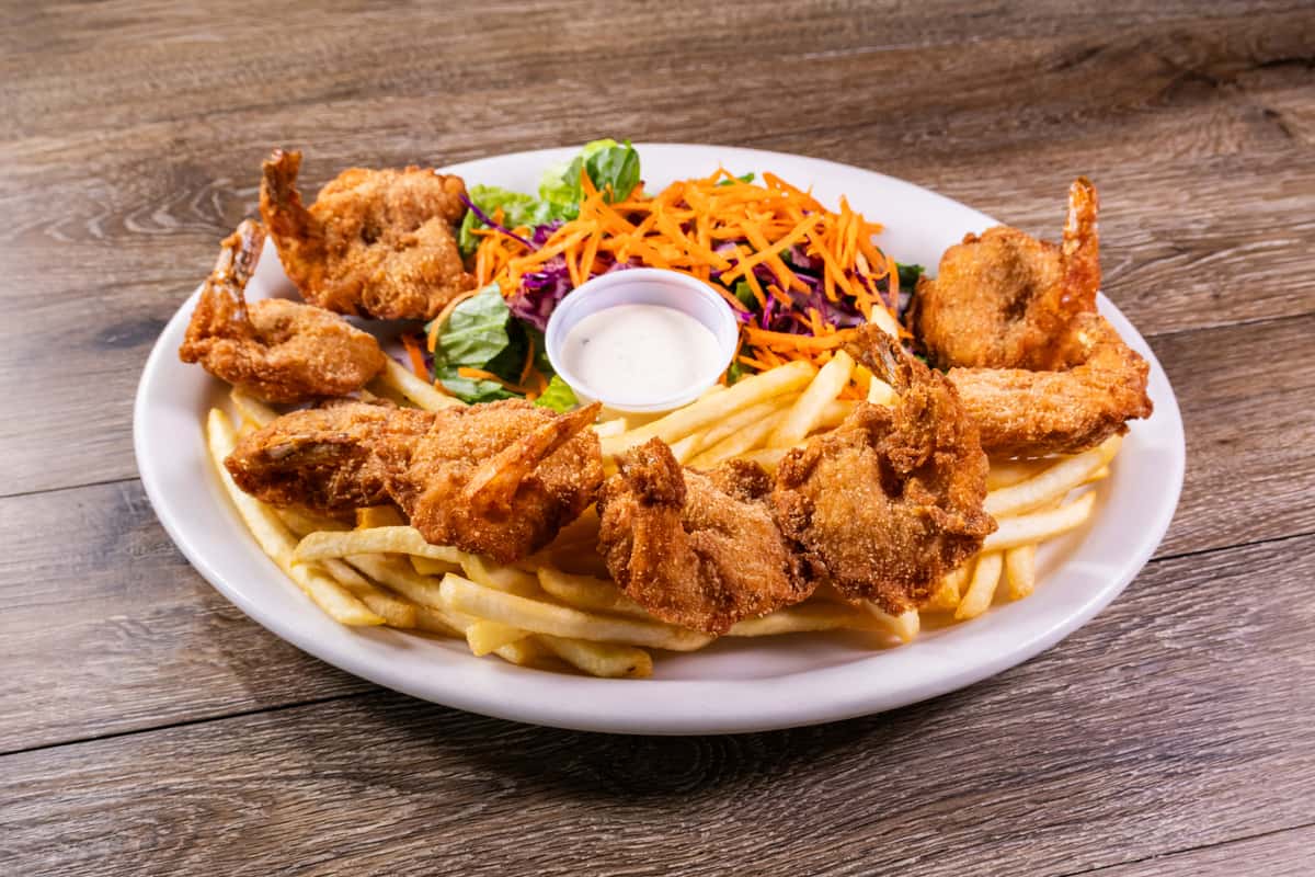 Golden fried butterfly shrimp served with crispy French fries, a fresh garden salad, and creamy ranch dipping sauce on a white plate.