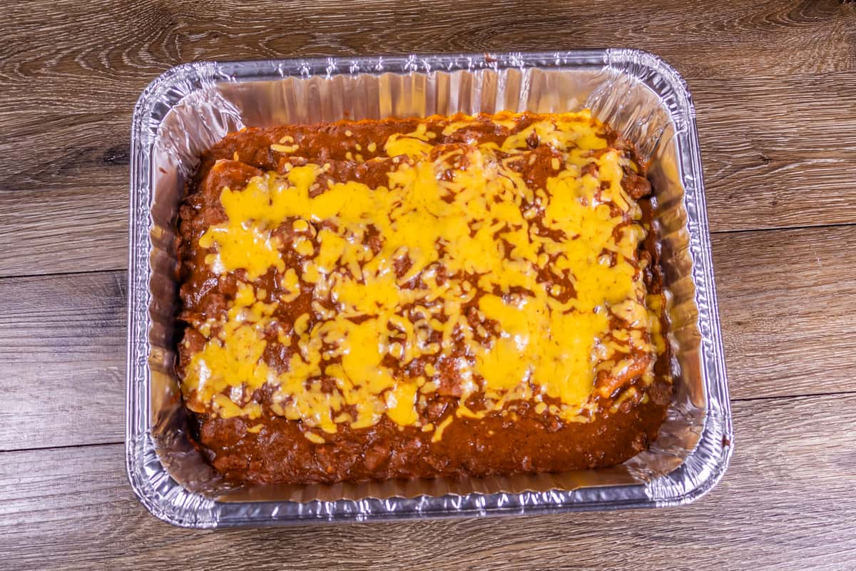 Family-size cheese enchiladas baked with savory chili gravy and melted cheddar cheese in a catering tray, perfect for takeout, parties, or group meals.