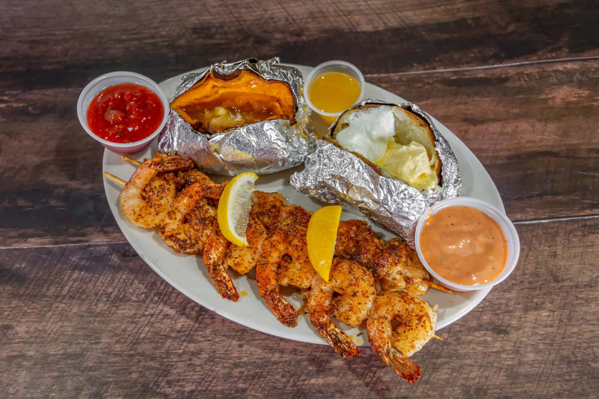 Close-up of a fried seafood platter at Cherry Pocket Steak & Seafood Shak, featuring crispy golden shrimp, hush puppies, and seasoned fries, served with dipping sauce on a casual dining table.