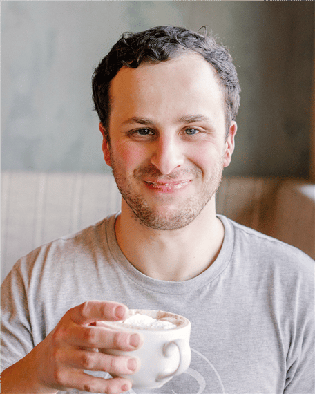 A man holding a coffee mug and smiling at The Sassy Biscuit brunch restaurant.