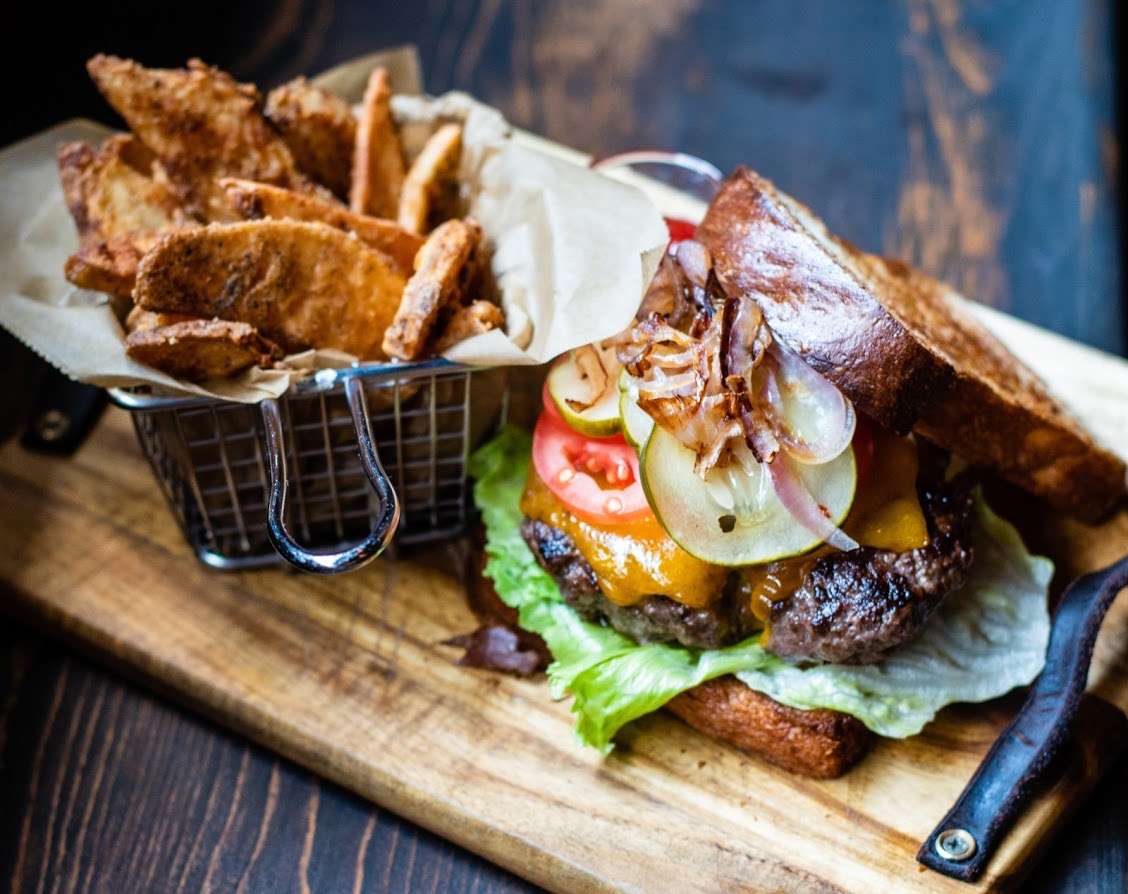 Gourmet cheeseburger with pickles, tomato, and crispy fries