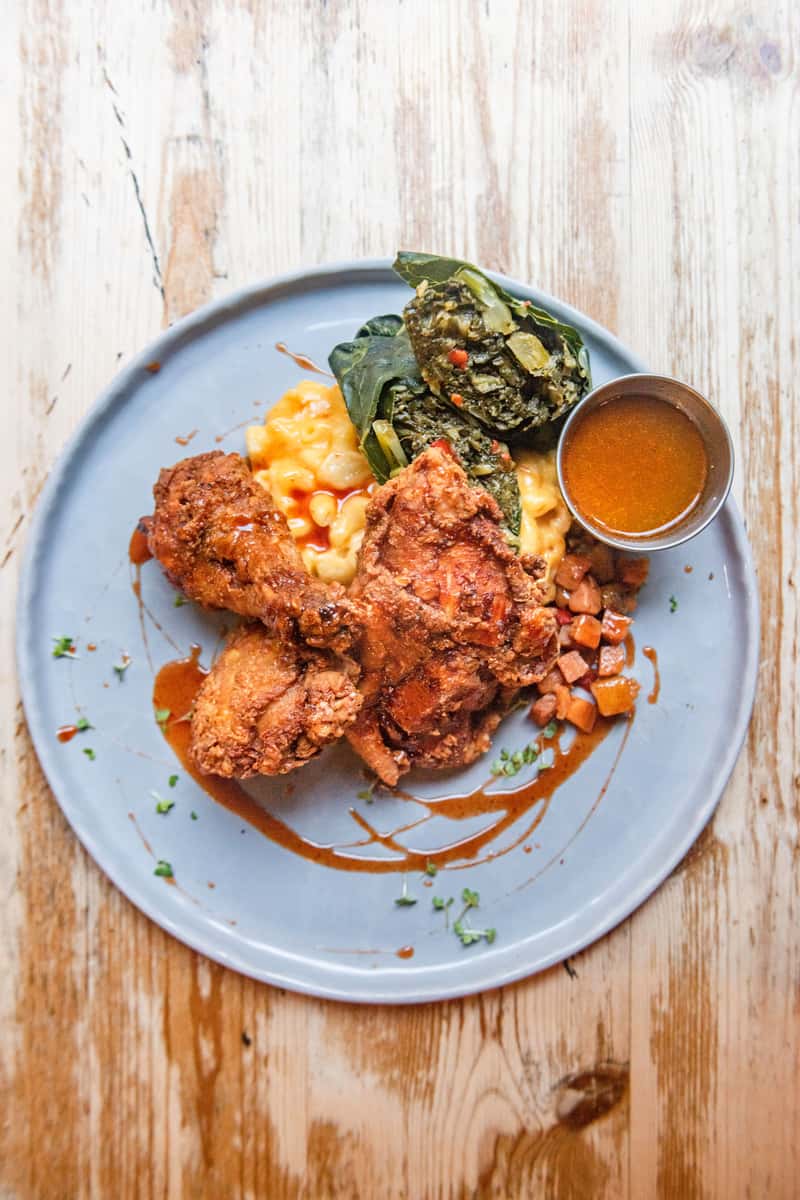 Fried chicken served with mac and cheese, collard greens, and brown gravy on a plate