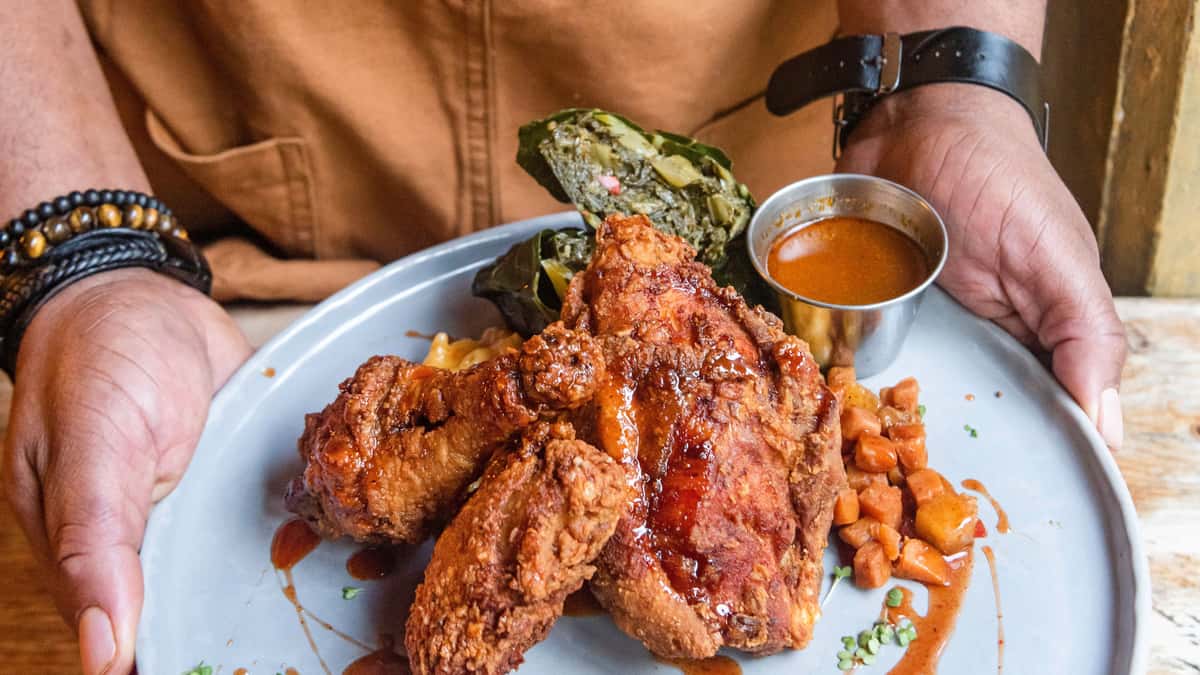Man holding a saucy chicken dish with a side of sauce