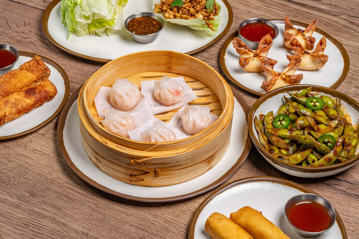 Assorted Asian appetizers including dumplings, lettuce wraps, egg rolls, spring rolls, edamame with jalapeños, and crab rangoon.