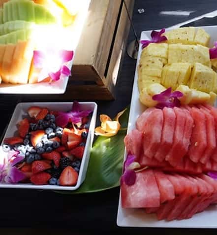 Trays and bowls filled with slices of fresh fruit and berries