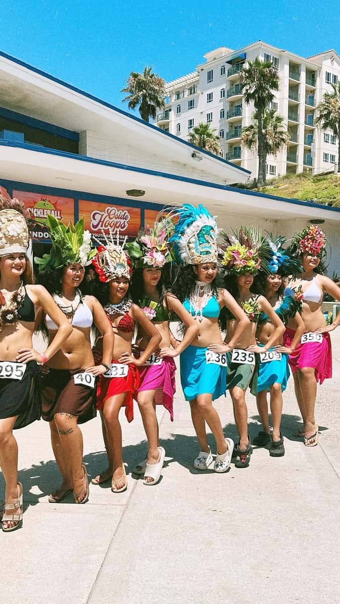 hula performers posing in traditional garments and head dresses.