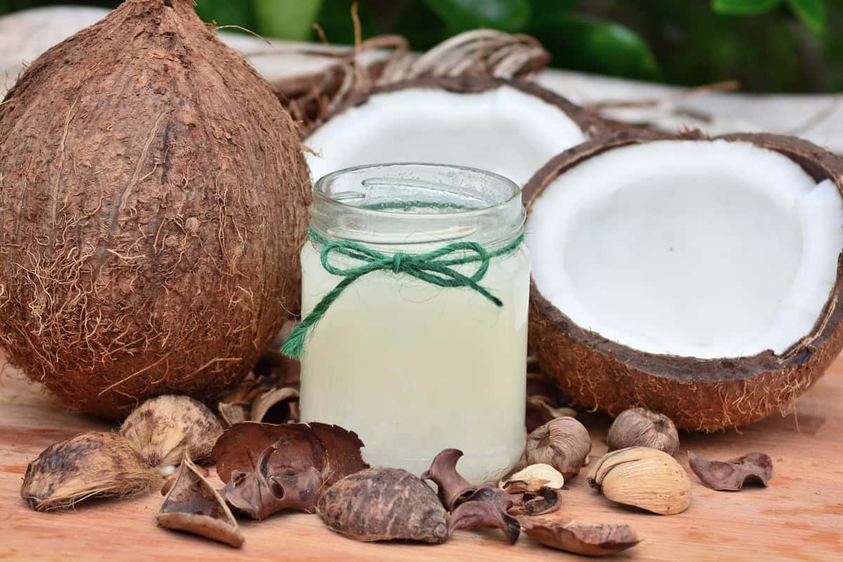 coconut and coconut oil on a table surrounded by coconut husk