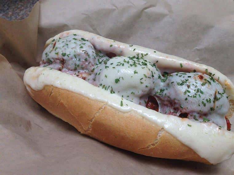 meatball sub sandwich with melted mozzarella garnished with sprinkles of parsley