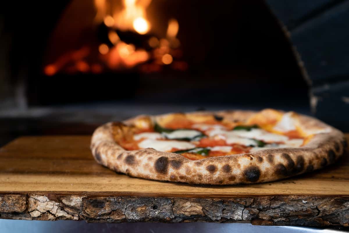 pizza in front of wood fired oven