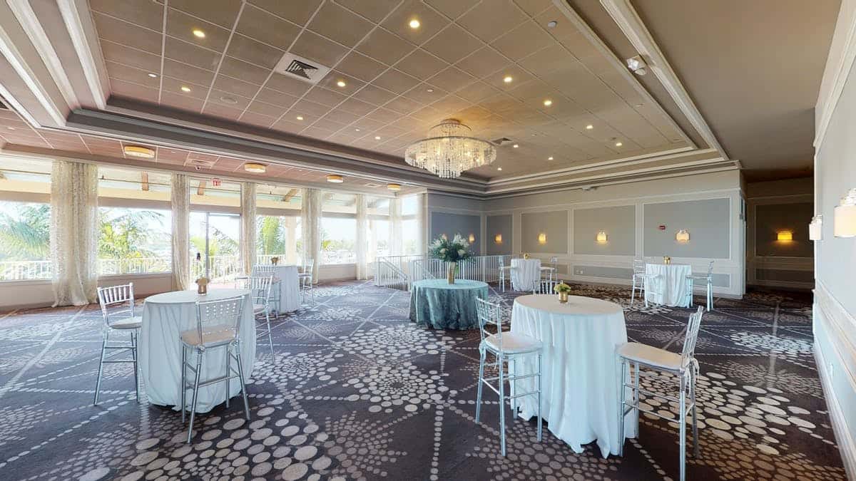 Elegant cocktail reception ballroom with chandelier lighting, high-top tables, and upscale event venue decor