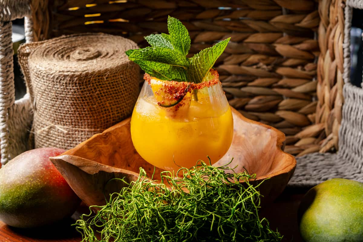 Tropical mango cocktail garnished with mint and chili rim served at a vibrant upscale bar and restaurant