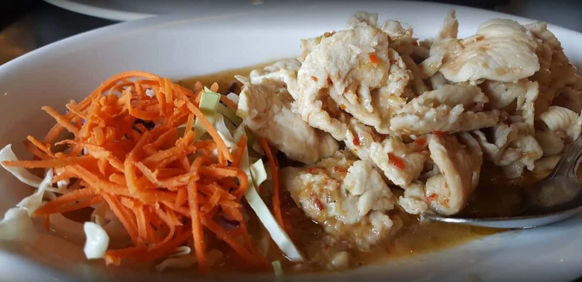 A close-up of a chicken or tofu stir-fry dish served with a side of shredded carrots