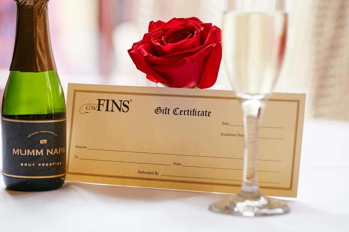 GW Fins gift certificate, red rose, and glass of champagne