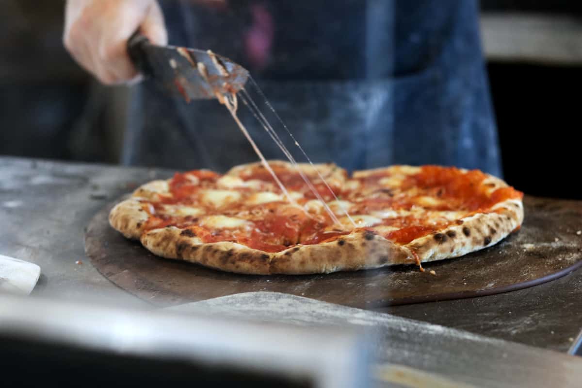Person cutting a pizza