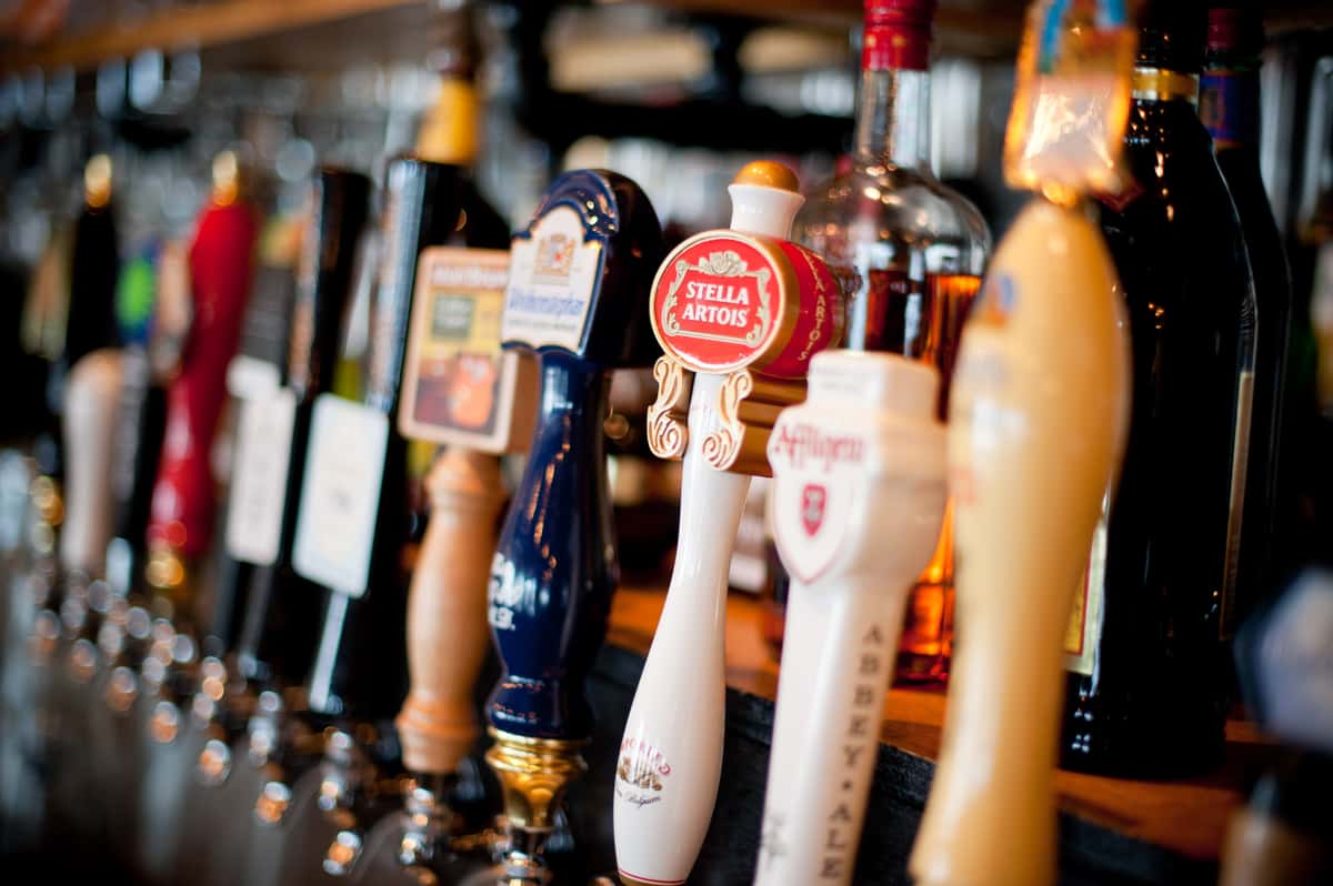Bar lineup with assorted craft beer taps including Stella Artois, set against a warm, softly lit restaurant backdrop