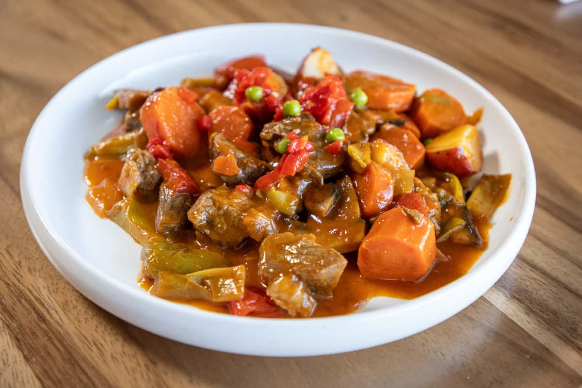 A hearty bowl of beef stew featuring chunks of meat, carrots, and potatoes in a rich gravy.