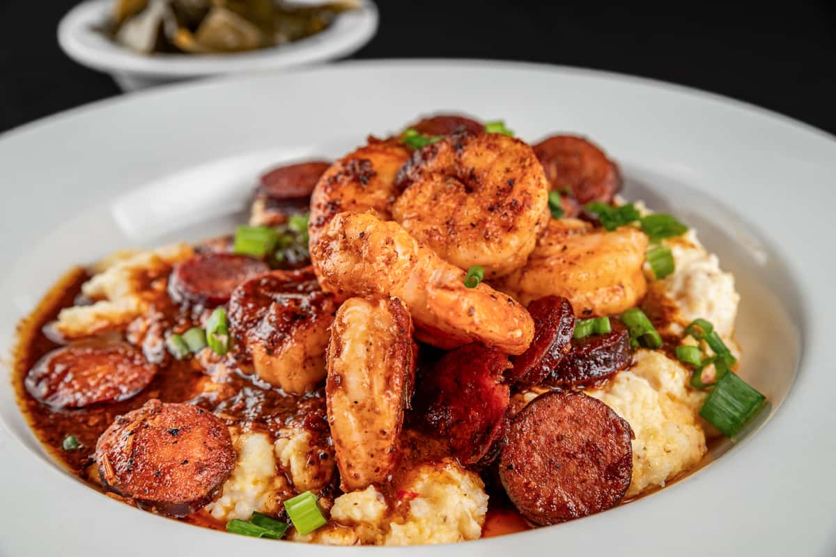 Southern-style shrimp and grits topped with sautéed shrimp, spicy andouille sausage, and scallions, served over creamy cheese grits with rich Cajun gravy.