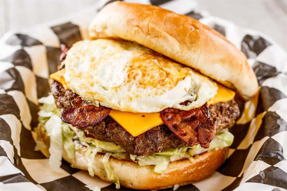 One (1/2 lb.) patty served with 2 slices of bacon, American cheese and a fried egg, bottomed with lettuce, tomatoes, onions and pickles. Your choice of condiments