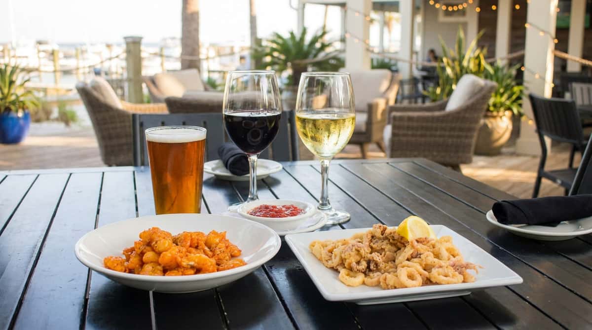 Fried calamari rings and tentacles with a side of red marinara sauce and a lemon wedge on a white plate.
