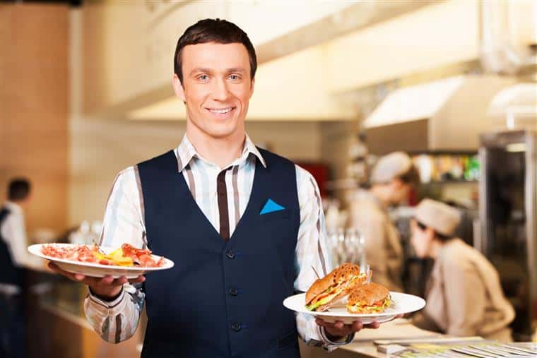 waiter smiling holding two plates of food