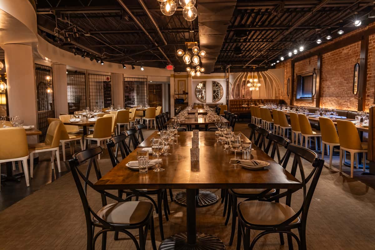 Spacious dining room with long communal table and modern lighting fixtures.