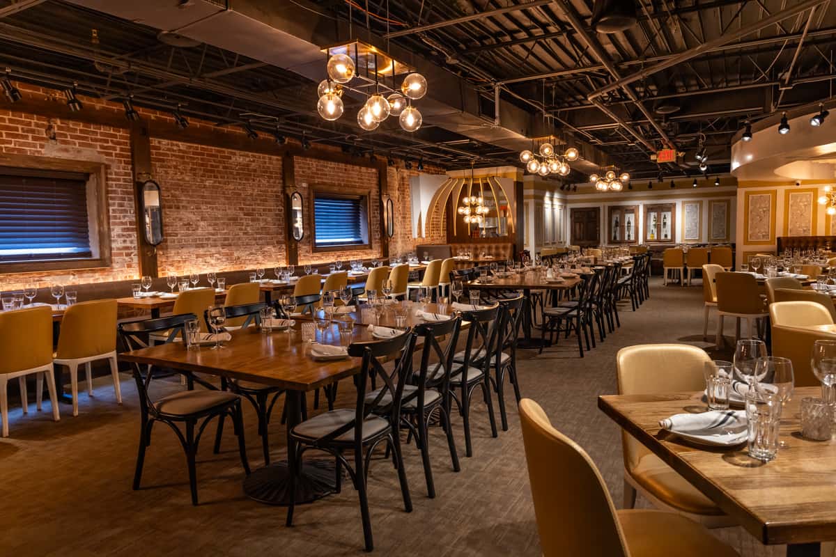Large restaurant dining area with exposed brick walls, wood accents, and set tables.
