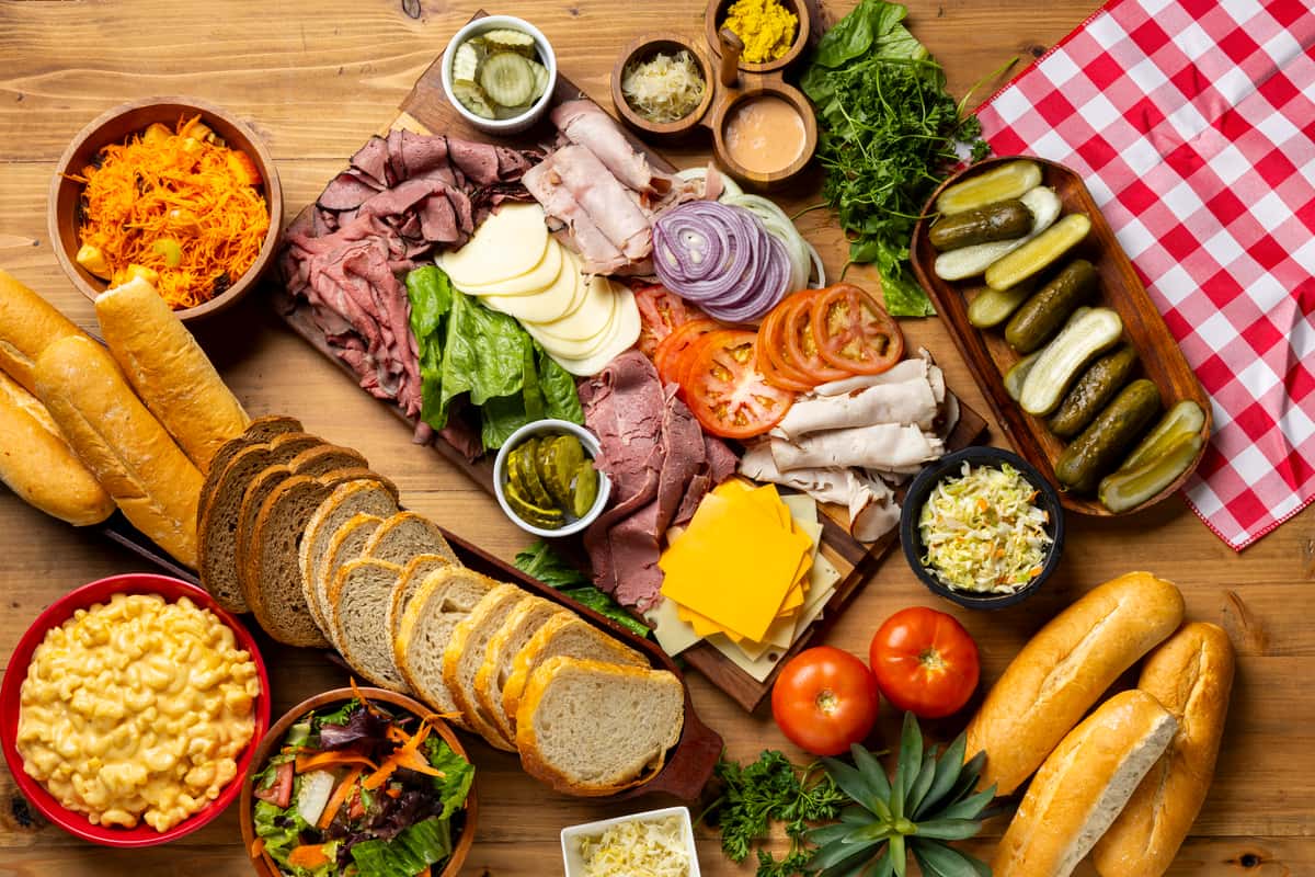 a spread of meats and cheeses, sides and bread