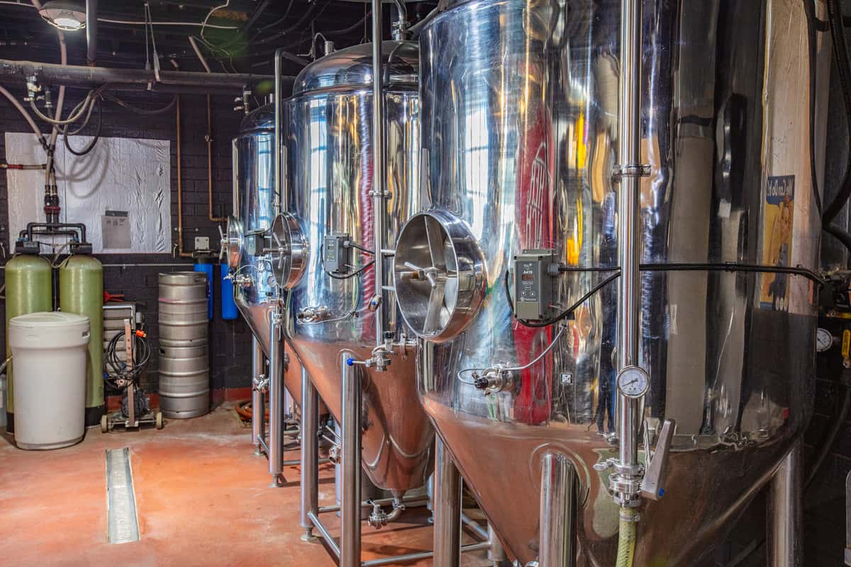 Rustic brewery interior featuring decorative chandeliers and warm wood ceiling beams creating a cozy ambiance