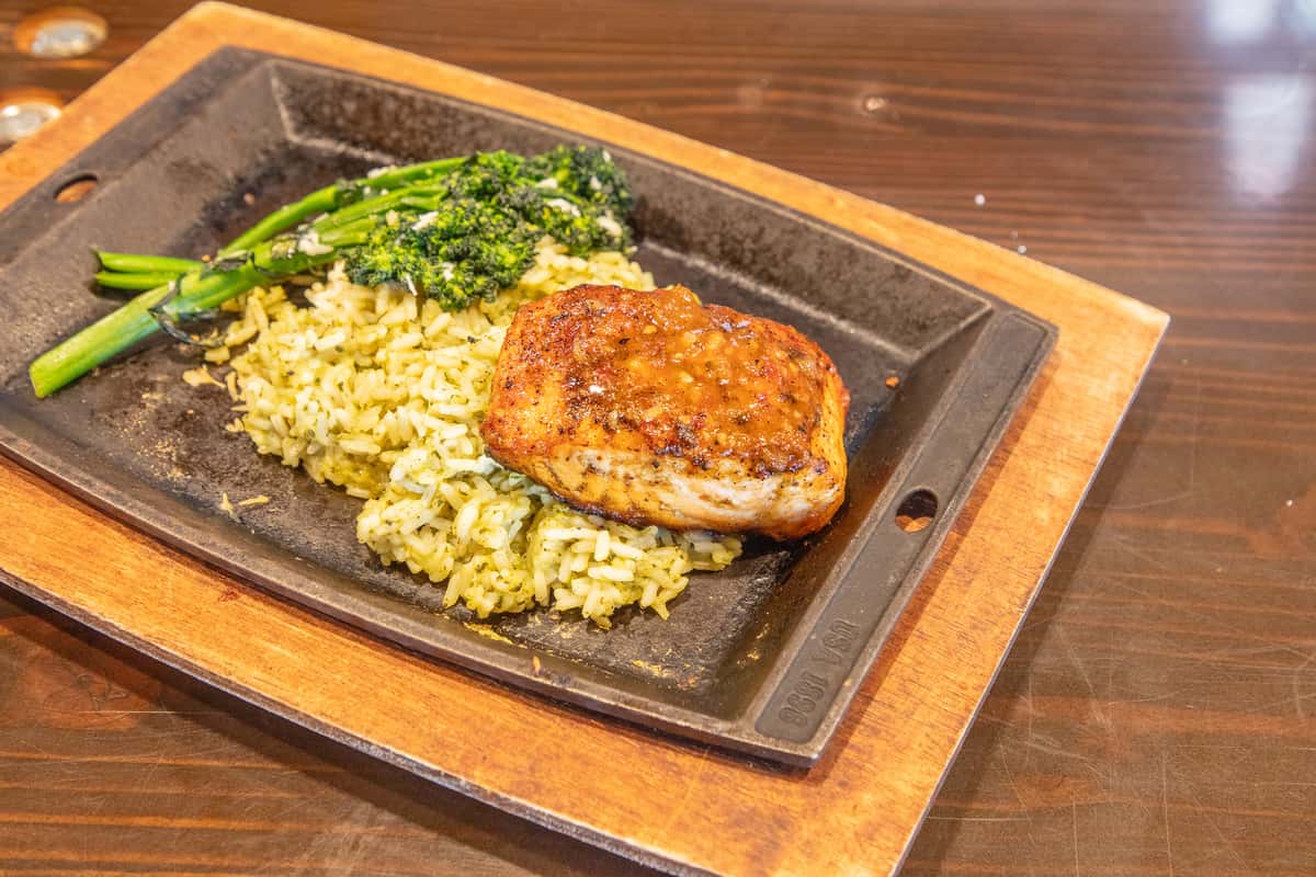 Grilled salmon fillet served with broccolini and grains on a hot skillet platter