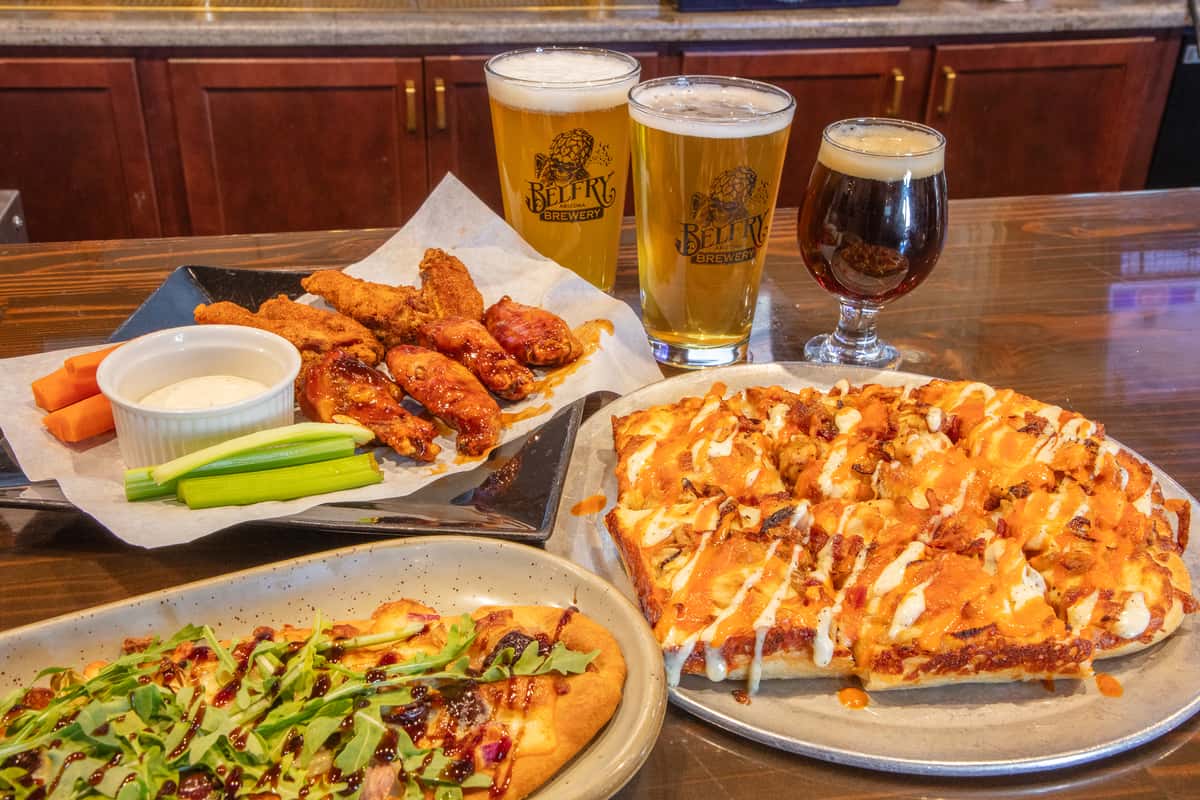 Assorted gourmet sliders with melted cheese and toppings served with craft beers and colorful cocktails on a brewery bar counter