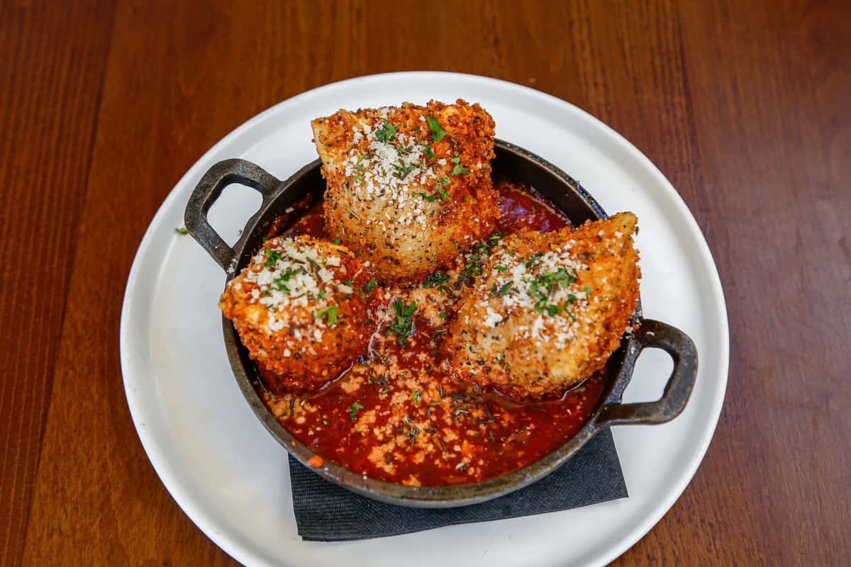 Crispy toasted ravioli topped with herbs and served with dipping sauce