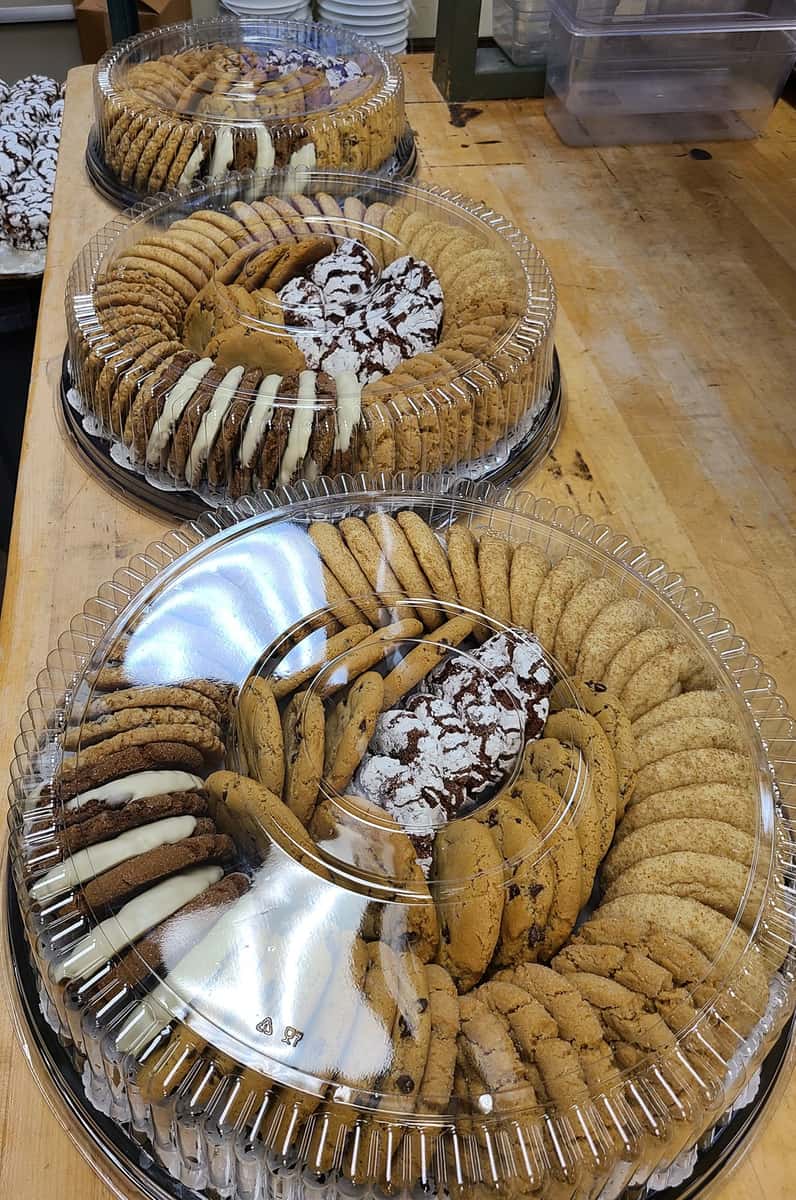 Assorted cookie trays with chocolate chip, crinkle, and frosted cookies in plastic containers