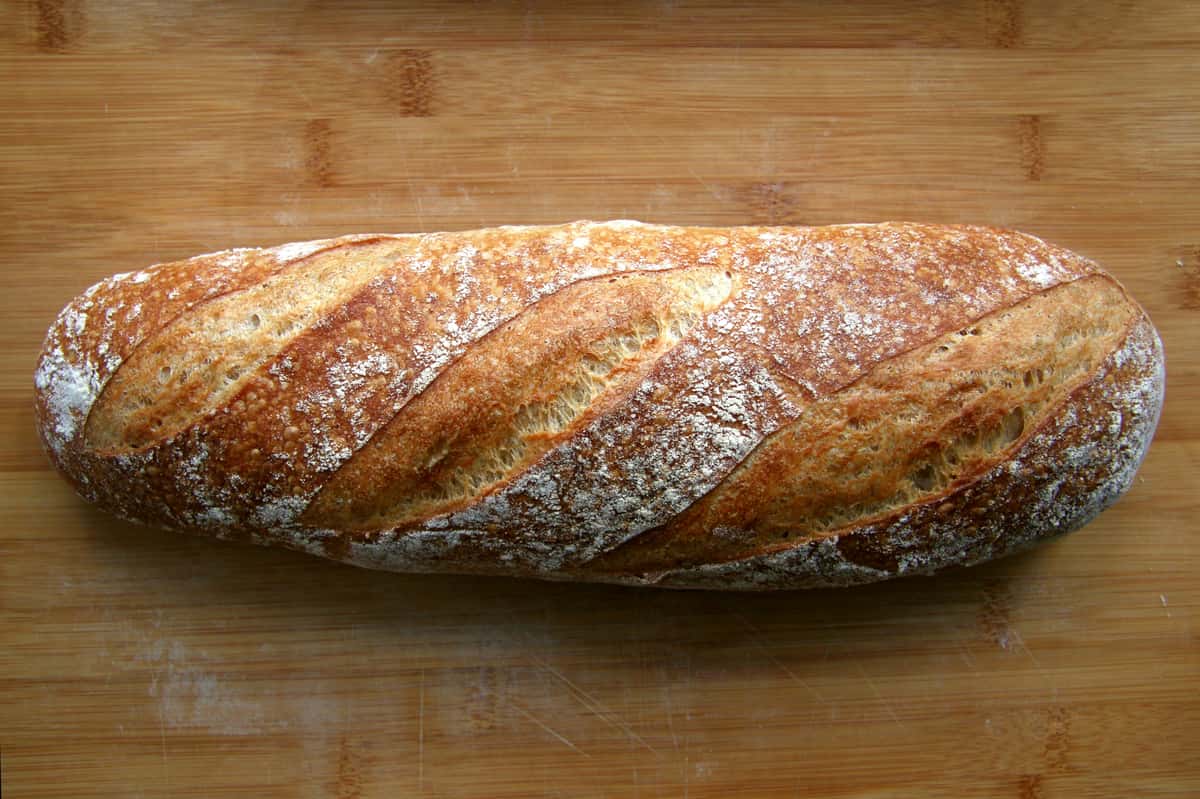 Crusty artisan loaf of bread on a wooden cutting board.