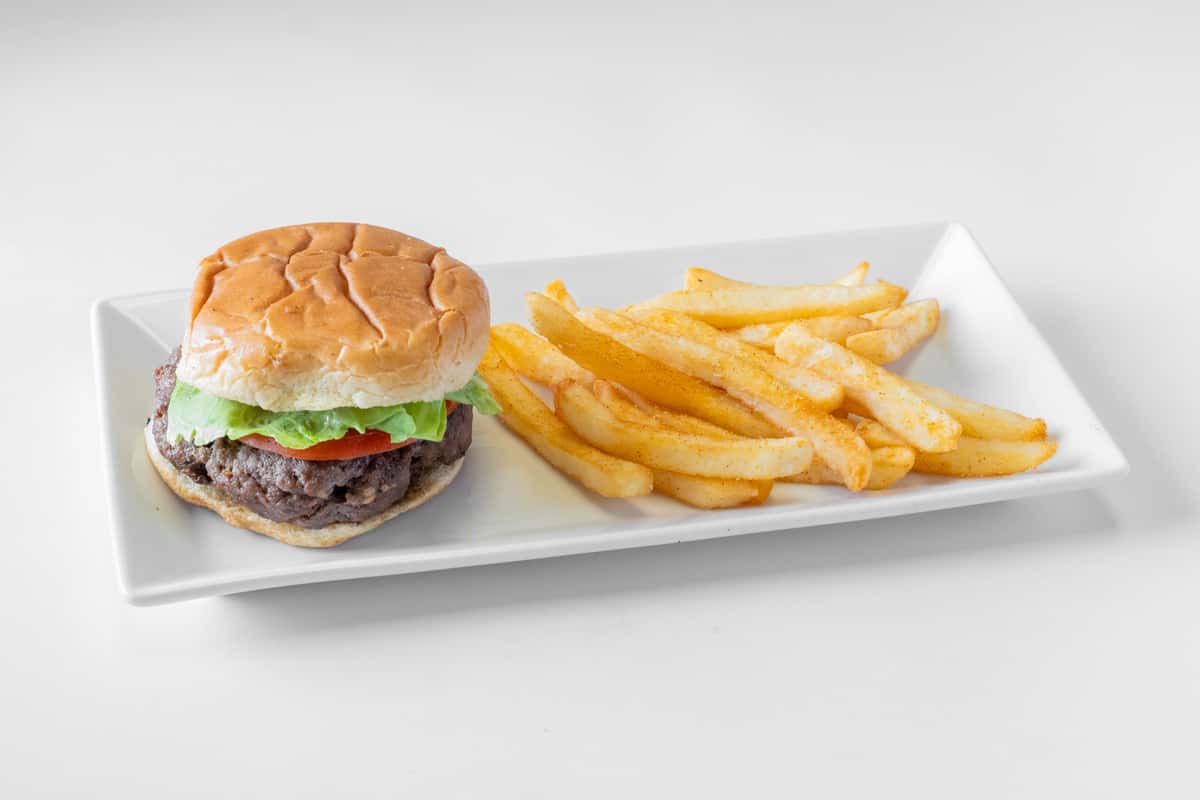 A juicy hamburger with lettuce and toppings served alongside golden french fries on a white plate