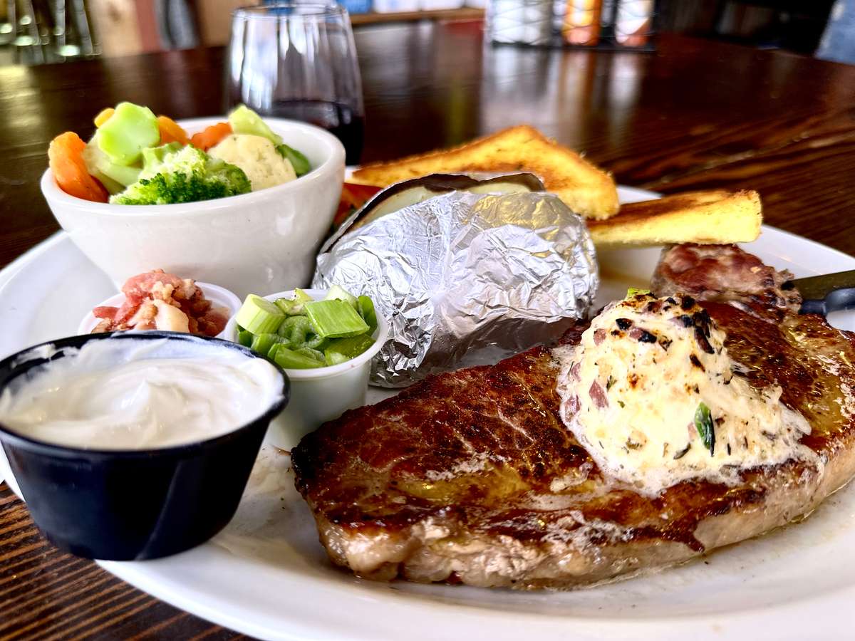 10oz New York steak served with a baked potato and all the fixins', Normandy style vegetables, and garlic toast.