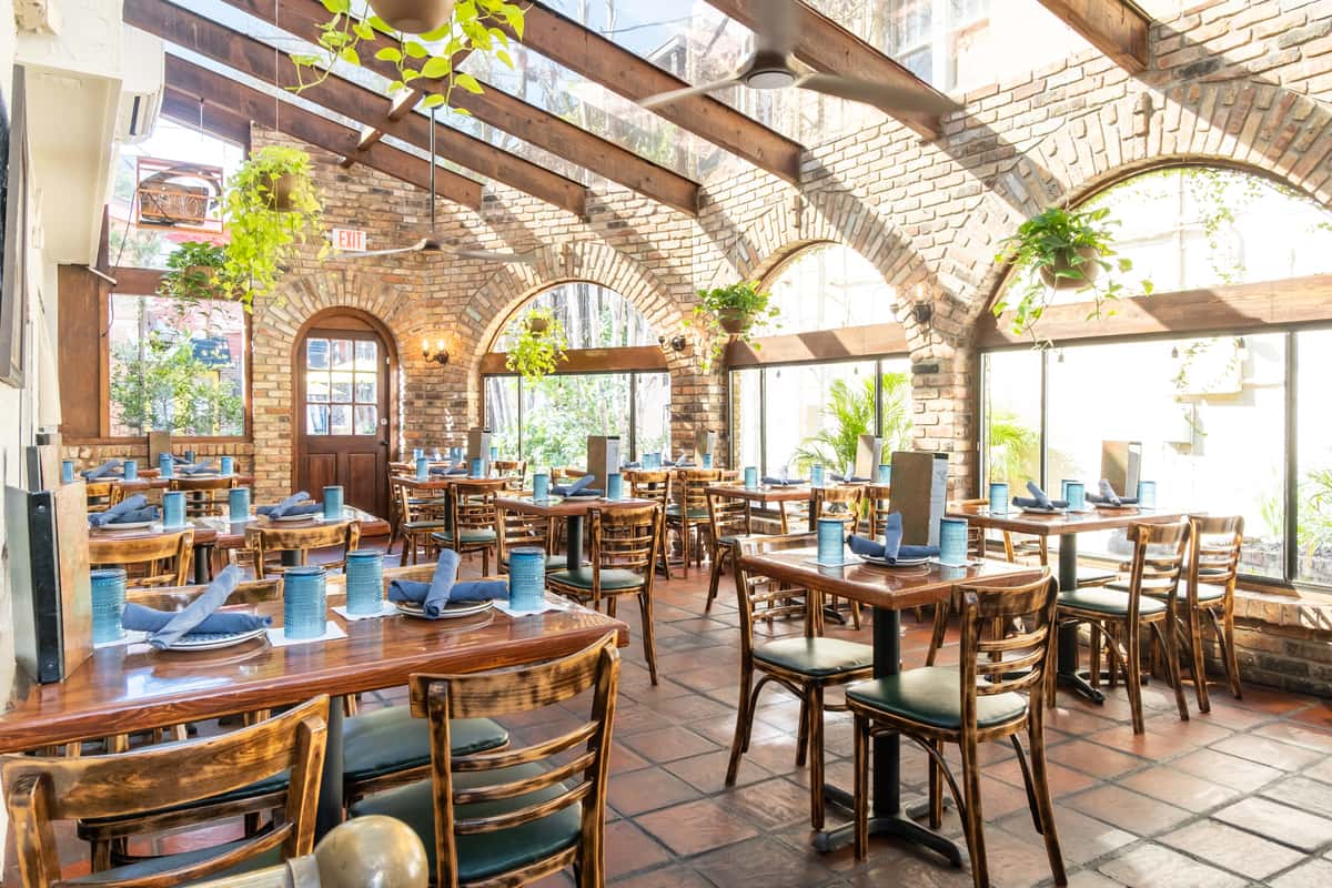 Patio dining area with hanging plants and open windows for sunlight